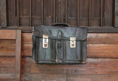 Ahşap sınıf arka planda asılı eski deri okul çantası.