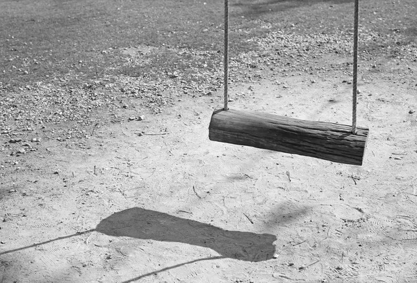 Empty swing with shadows in black and white style