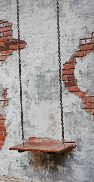 Empty chain swing against old brick wall background