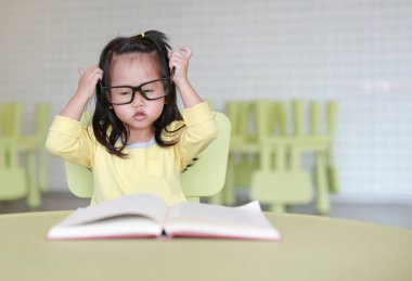 Zeki küçük çocuk kız çocuk odası bir kitap okuma gözlüklü.