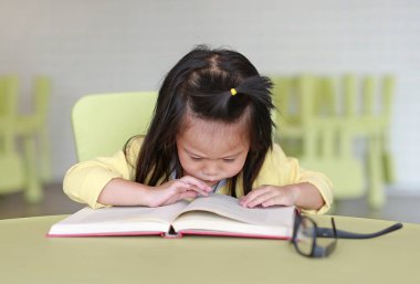 Zeki küçük çocuk kız çocuk odası bir kitap okuma niyetinde.