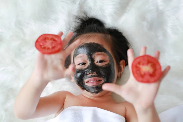 Menina Criança Carvão Descascamento Máscara Facial Segurando Fatias Tomate Nas — Fotografia de Stock