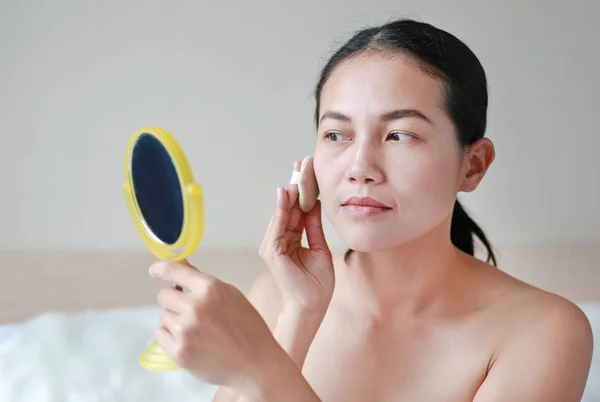Beauty asian woman applying makeup with Sponge Powder Puff. Woman make up herself.