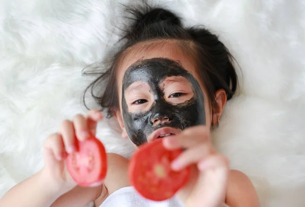 Menina Criança Carvão Descascamento Máscara Facial Segurando Fatias Tomate Nas — Fotografia de Stock