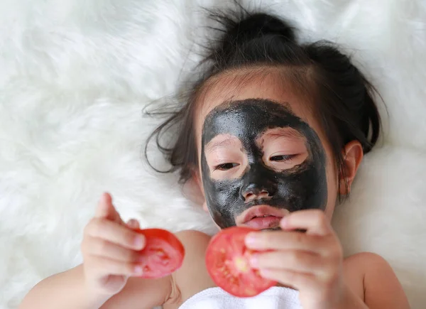 Menina Criança Carvão Descascamento Máscara Facial Segurando Fatias Tomate Nas — Fotografia de Stock