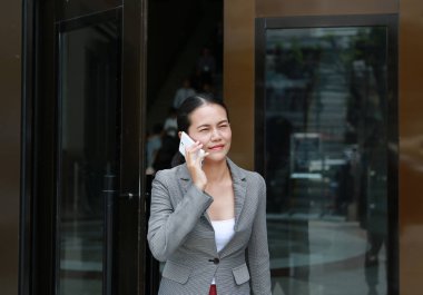 Açık kapı ile telefon kullanarak ve dışında yürüyüş güzel genç iş kadını.