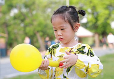 Sevimli küçük kız plastik hava pompası balon parkta güneşli bir günde kullanarak..