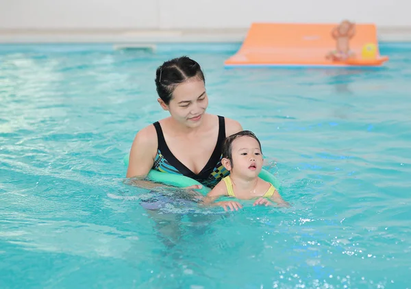 Close up mother teaching kid in swimming pool