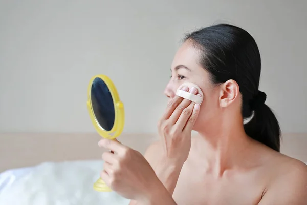 Beauty asian woman applying makeup with Sponge Powder Puff. Woman make up herself.