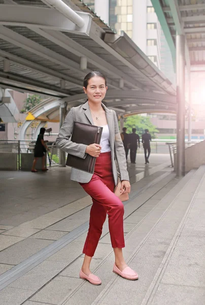 Beautiful young business woman walking outside. Asian businesswoman office worker in downtown business district.