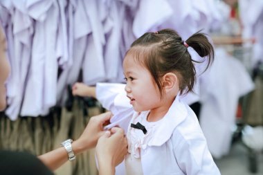 Anne kızı anaokulu çocuk için okul üniforması soyunma deneyin.