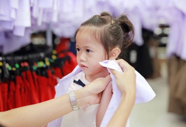 Anne kızı anaokulu çocuk için okul üniforması soyunma deneyin.