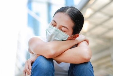 Woman wearing protective mask to protect pollution and the flu sitting at public area. clipart