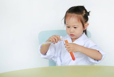 Beyaz arka plan, bilim adamı kimya ve eğitim kavramı üzerinde izole sıvı ile test tüpü tutan bilim adamı üniformalı Asyalı çocuk.