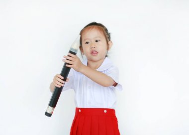 Beyaz arka plan üzerinde izole büyük kalem tutan okul üniformalı Asyalı çocuk portresi.