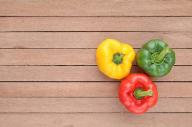 Ahşap arka plan üzerinde kopya alanı ile yeşil, kırmızı ve sarı dolmalık biber.