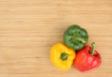 Ahşap arka plan üzerinde kopya alanı ile yeşil, kırmızı ve sarı dolmalık biber.