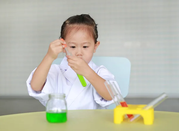 Asian child in scientist uniform holding test tube with liquid, Scientist chemistry and science education concept.