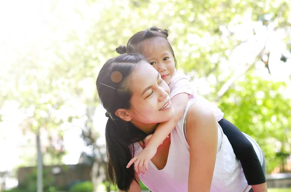 Glückliches Kleines Mädchen Auf Dem Rücken Ihrer Mutter Garten — Stockfoto
