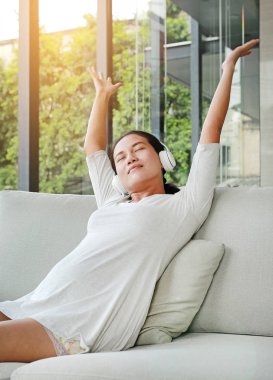 Hamile kadın oturuyor ve kanepe kulaklık müzik dinleme dinlenin.