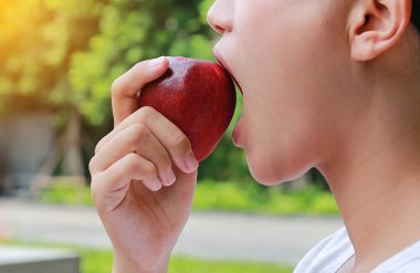 Genç Asyalı kız yan görünüm bir elma yiyor.