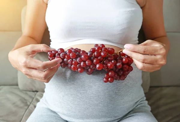 怀孕妇女在她的腹部紫葡萄 健康食品概念 — 图库照片