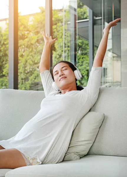 Hamile kadın oturuyor ve kanepe kulaklık müzik dinleme dinlenin.