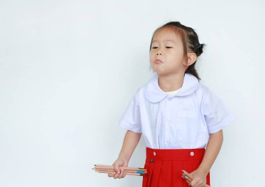 Beyaz arka plan üzerinde izole renk kalem tutan okul üniformalı Asyalı çocuk portresi.