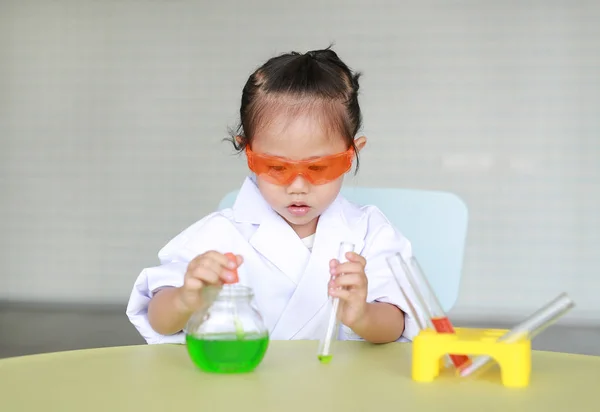 Asian child in scientist uniform holding test tube with liquid, Scientist chemistry and science education concept.