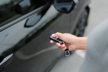 Kadın el kilitlemek veya araba kilidini açmak için uzaktan kumandanın düğmesine basarak