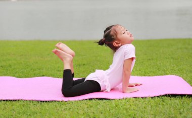 Genel parkta yoga yaparken küçük Asyalı çocuk kız portresi.