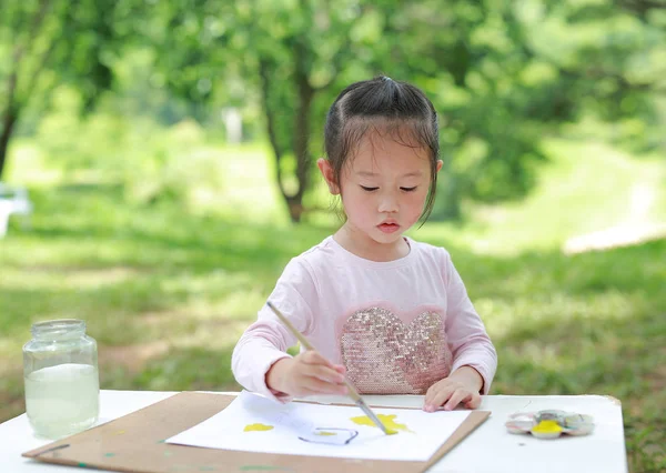 Ευτυχισμένο Παιδί Κάθεται Στο Τραπέζι Και Ζωγραφική Πινέλο Στο Χαρτί — Φωτογραφία Αρχείου