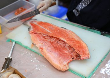 Şef, bir kesme tahtası üzerinde somon keser. Deniz ürünleri yemek için madde.