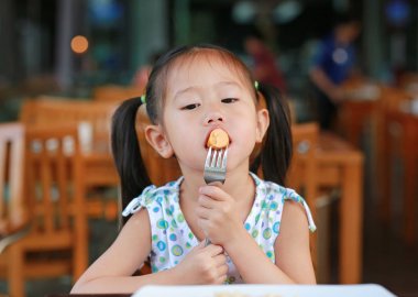 Küçük kız restoranda kahvaltı için sosis.