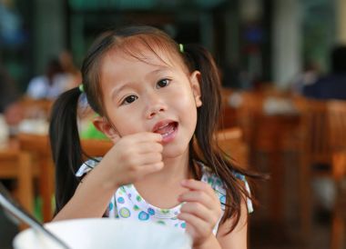 Kahvaltı restoranda gülümseyen küçük Asyalı kız