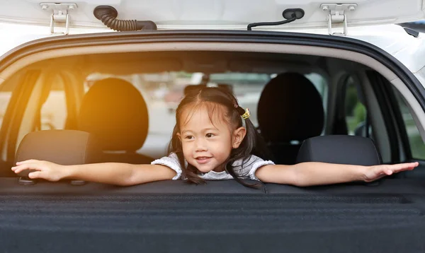 幸福的亚洲儿童女孩躺在汽车的掀背门 — 图库照片