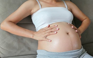 Hamile kadının karın derisinin üzerinde krem uygulamak. Hamilelik sırasında kuru cildi nemlendirmek.