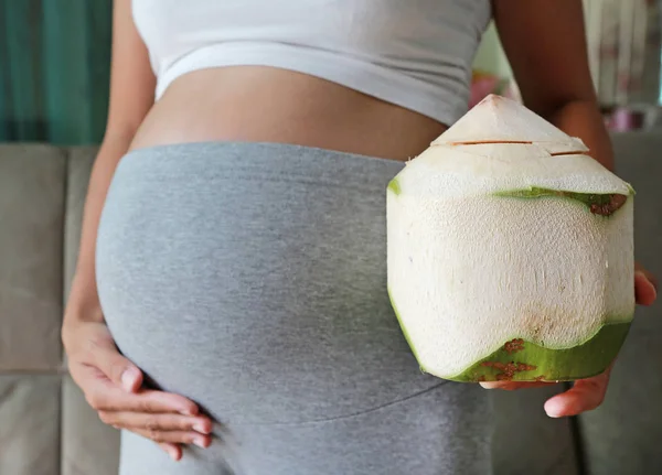 Schwangere Steht Zimmer Und Hält Frische Kokosnuss Bauch — Stockfoto