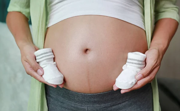 Břicho Těhotné Ženy Dětskými Ponožky — Stock fotografie