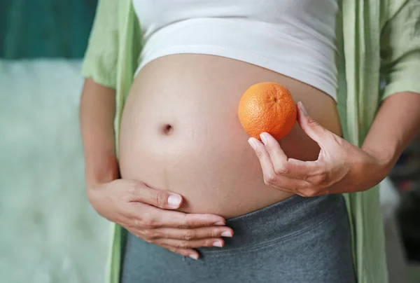 怀孕妇女在她的腹部举行橙果子 — 图库照片