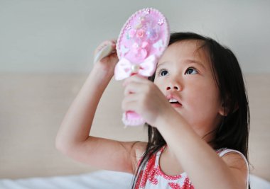 Sevimli küçük kız arıyor ile onun saç tarama elinde ayna.