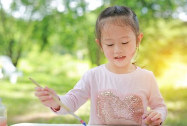Çocuk resim, yeşil bir bahçe içinde kağıt üzerine boyanacak küçük kız eğleniyor.