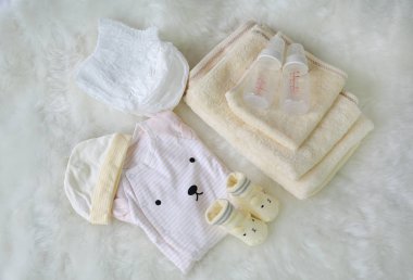 Koleksiyon öğeleri bodysuits çorap süt şişesi ve beyaz kürk arka plan havlu ile yeni doğan bebekler için