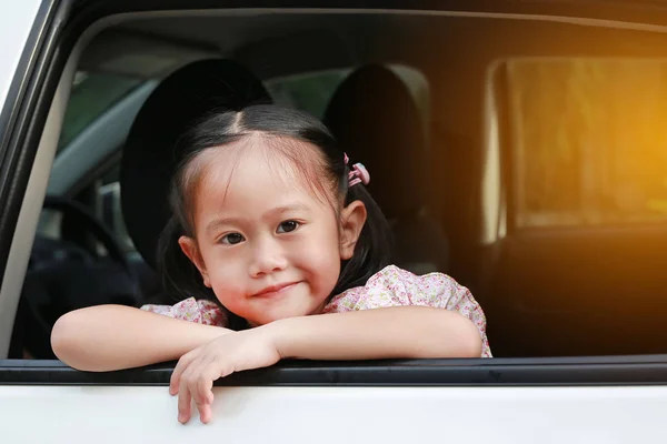 可爱的小亚洲女孩看着相机从窗口的汽车与阳光光线 — 图库照片