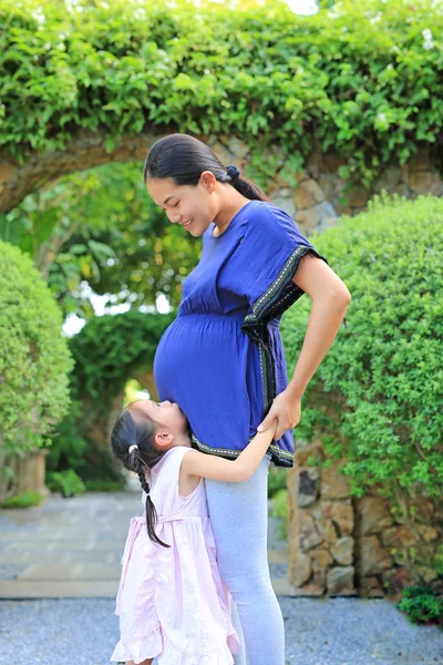 Χαριτωμένο Κοριτσάκι Που Αγκαλιάζει Έγκυος Μητέρα Στον Κήπο — Φωτογραφία Αρχείου
