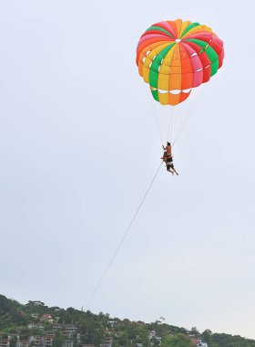 İnsanlar parasailing su sporları tadını çıkarın. Plaj üzerinde gökyüzü üzerinde renkli paraşüt ile çeneni kapat.