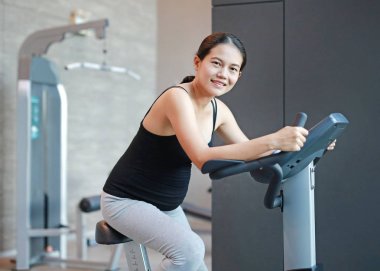 Hamile kadın egzersiz spor salonunda bisikletle.