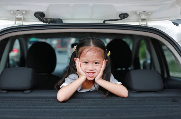 滑稽的面孔小亚洲孩子看照相机从汽车的窗口 — 图库照片