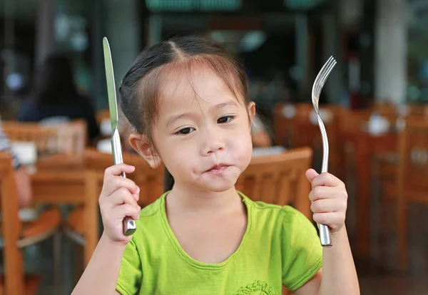 Urocza Dziewczynka Azjatyckich Trzymając Nóż Widelec Siedząc Fotelu Drewna Restauracji — Zdjęcie stockowe