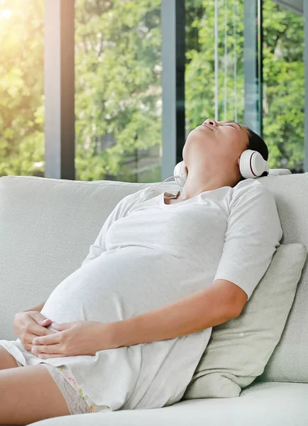 Mulher Grávida Está Sentada Sofá Ouvindo Música Fones Ouvido Smartphone — Fotografia de Stock